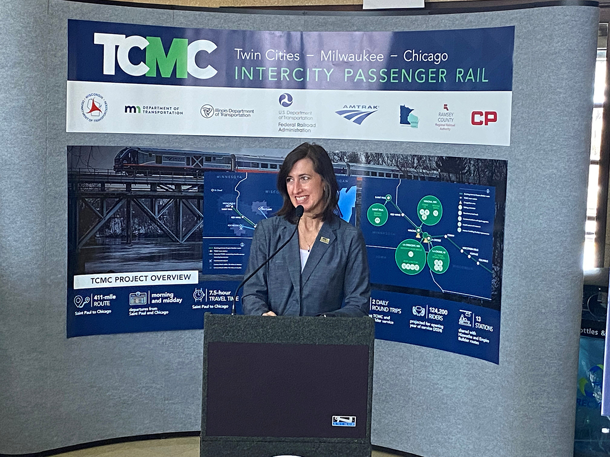 Photo: Nancy Daubenberger, MnDOT interim commissioner, speaks in front of a photo backdrop of the future second daily round-trip train between Twin Cities and Chicago.